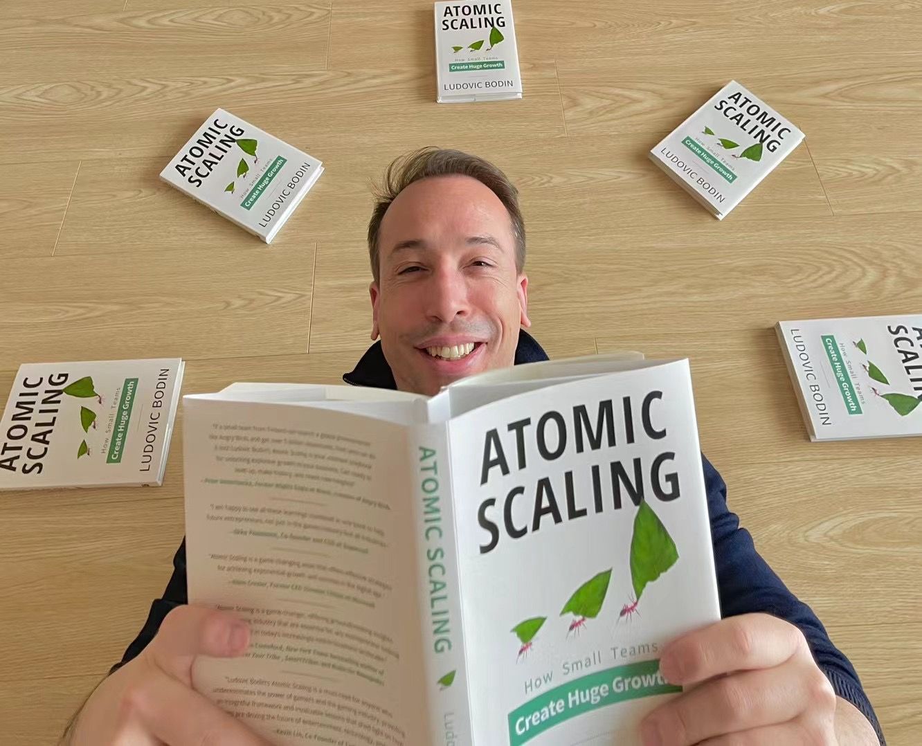 Ludovic Bodin smiling, surrounded by copies of his book Atomic Scaling